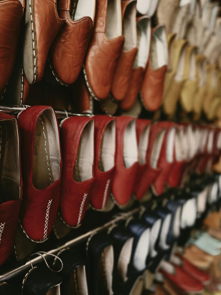 Close-up view of various leather shoes hanging in a retail display showcasing vibrant colors.